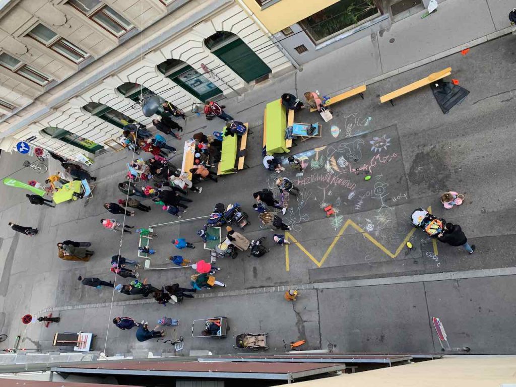 Photo of a street closed to traffic with people playing games and talking in Vienna.